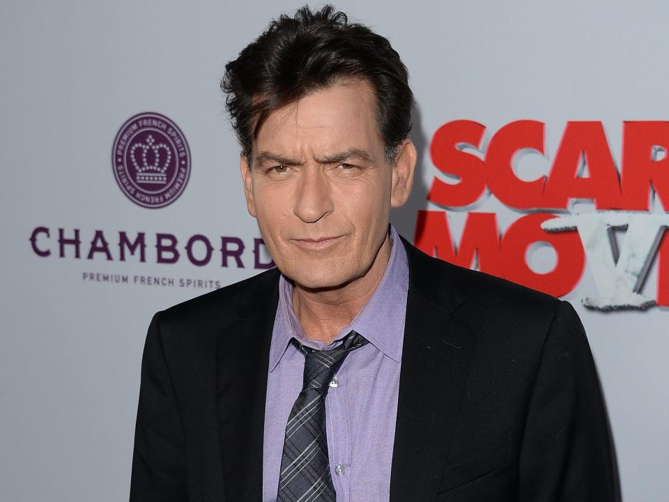Charlie Sheen in front of red carpet wall
