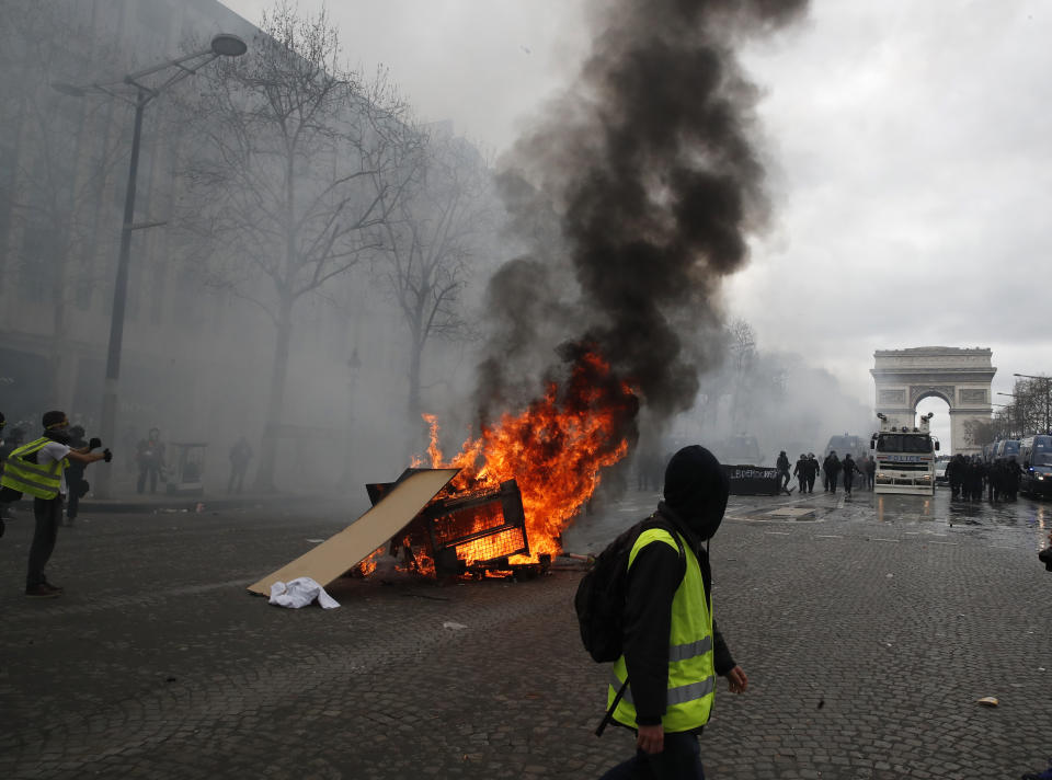 A barricade burns on the Champs Elysees avenue Saturday, March 16, 2019 in Paris. French yellow vest protesters clashed Saturday with riot police near the Arc de Triomphe as they kicked off their 18th straight weekend of demonstrations against President Emmanuel Macron. (AP Photo/Christophe Ena)