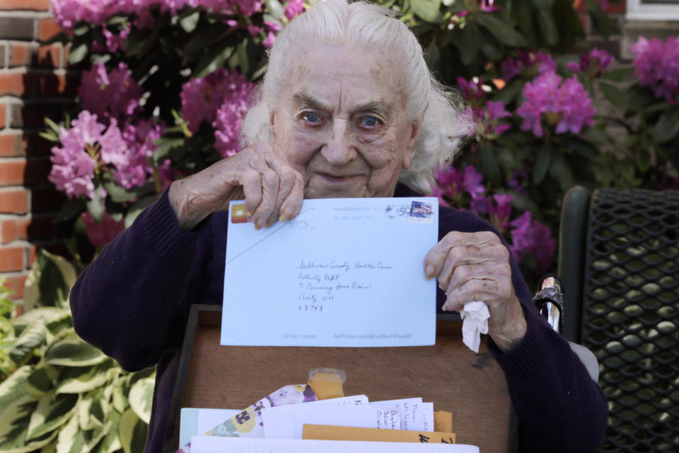 In this Monday, June 8, 2020, photo, 93-year-old Flo Young, originally from Cambridge, Mass., holds up a pen pal letter outside the Sullivan County Health Care nursing home in Unity, N.H. In a letter-writing effort during the virus pandemic to connect nursing home residents in two neighboring communities, residents now are receiving pen pal letters from across the United States. (AP Photo/Charles Krupa)