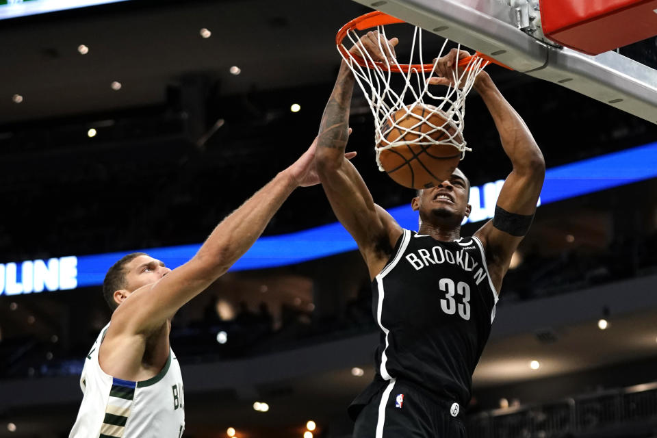 Brooklyn Nets' Nic Claxton (33) dunks next to Milwaukee Bucks' Brook Lopez during the first half of an NBA preseason basketball game Wednesday, Oct. 12, 2022, in Milwaukee. (AP Photo/Aaron Gash)