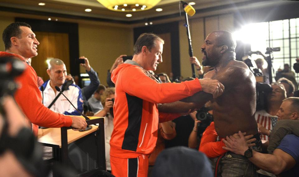 Former heavyweight world champion Shannon Briggs of the US, is pushed back by security after showing up at a press conference of boxer Wladimir Klitschko, left, of Ukraine during a press conference ahead of Klitschko's IBF, IBO, WBO and WBA heavyweight title bout against challenger Alex Leapai from Australia-Samoa in Duesseldorf, Germany, April 22, 2014. Briggs demanded a title fight against Klitschko in the US. (AP Photo/Martin Meissner)