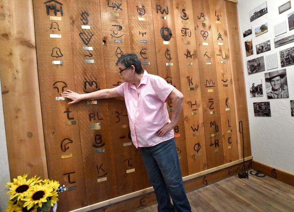 Carolyn Harbin points to one of the unique brands on a wall filled with them at the Dublin Rodeo Heritage Museum on July 21. The museum is marking 20 years this summer.