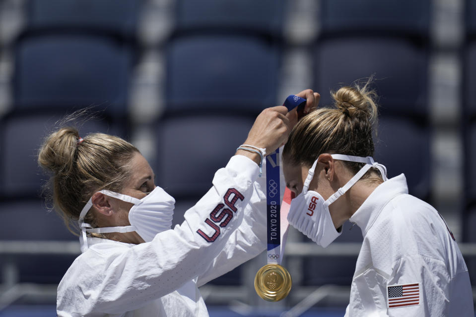 April Ross, left, of the United States, places the gold medal around the neck of teammate Alix Klineman, after winning a women's beach volleyball Gold Medal match against Australia at the 2020 Summer Olympics, Friday, Aug. 6, 2021, in Tokyo, Japan. (AP Photo/Felipe Dana)