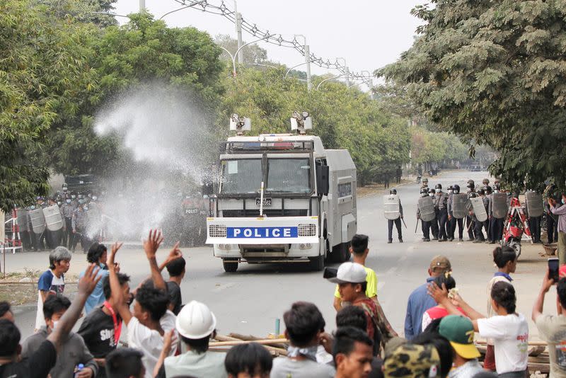 Police officers stand in front of people who protest against the military coup, in Mandalay