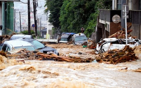 Cars are damaged by floodwater as heavy rain continues in Hiroshima, Japan - Credit: Getty