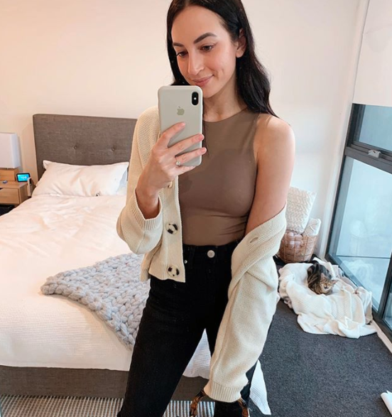 Woman taking a selfie in the mirror wearing a kmart cardigan and a brown high-nick Zara top