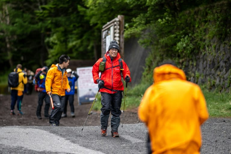 Des randonneurs franchissent un guichet nouvellement installé pour accéder au sentier Yoshida conduisant au mont Fuji au Japon, le 1er juillet 2024 (Philip FONG)