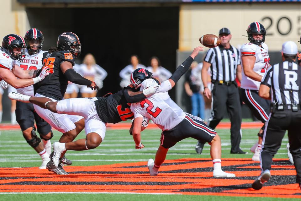 Oklahoma State's Collin Oliver (30) takes down Texas Tech's Behren Morton (2) as he throws the ball in the first quarter during a college football game between the Oklahoma State Cowboys and the Texas Tech Red Raiders at Boone Pickens Stadium in Stillwater, Okla., Saturday, Oct. 8, 2022.