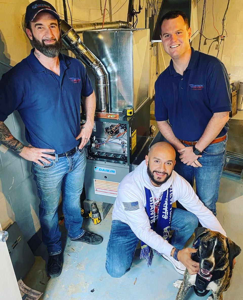 Sergio Agudelo (kneeling) with his newly installed furnace and two of the Tom Rostron Co. employees who helped make it happen.