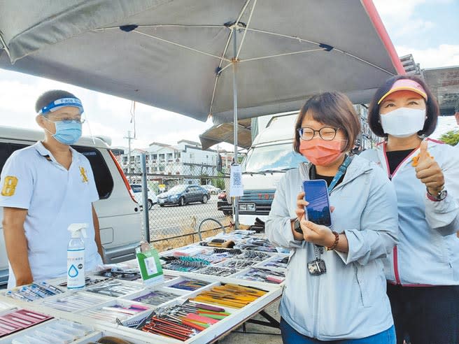 中央疫情指揮中心4日頒布5項重點管制措施，雙北及高雄的夜市認為可以做得到，也呼籲民眾買了就走，切勿逗留。圖為雲林縣西螺鎮東南夜市4日演練微解封，一名賣生活小物的攤販提供掃Line Pay付款，當場測試行得通，右為雲林縣長張麗善。（周麗蘭攝）