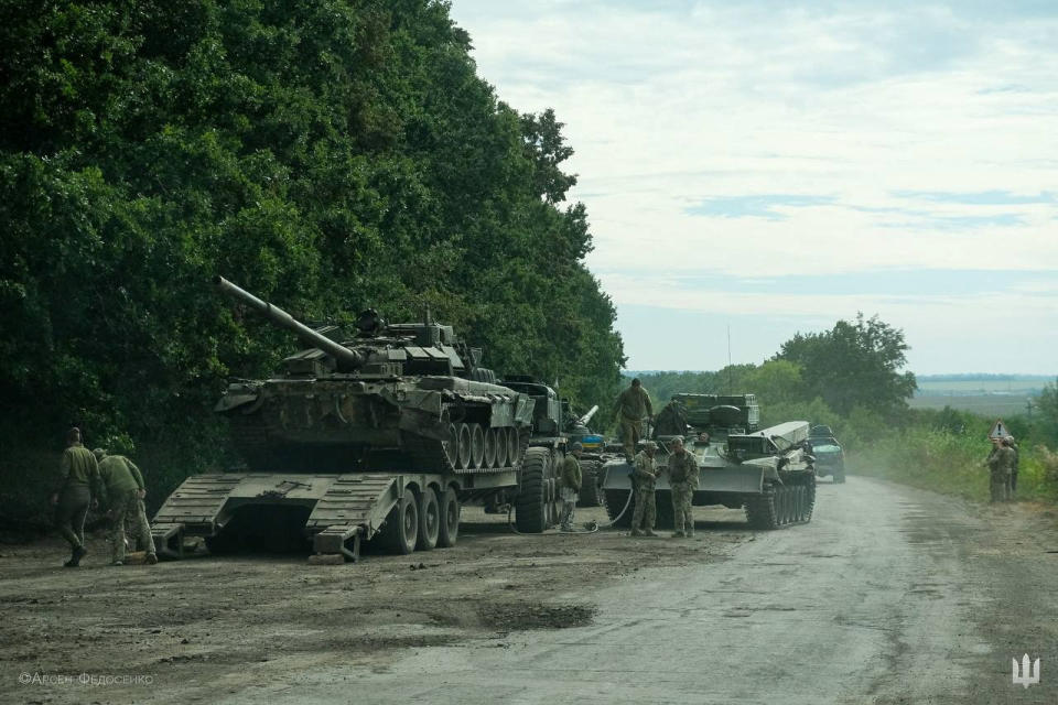 Ukrainian service members prepare to transport a Russian tank captured during a counteroffensive operation