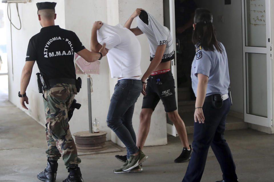 Suspects cover their faces with their shirts as they arrive at the Famagusta courthouse in Paralamni, Cyprus, Friday, July 26, 2019. A Cyprus court has ordered seven Israelis who were vacationing on the east Mediterranean island nation to be detained after a 19-year-old British woman alleged that she was raped in the resort town of Ayia Napa. (AP Photo/Petros Karadjias)