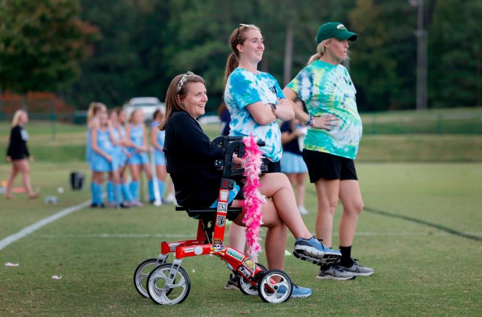 Ravenscroft High School field hockey coaches Whitford Wooten, left, Sydney Rameyan, center, and Meegan Hornan watch the team’s game against St. Mary’s School in Raleigh, N.C., Tuesday, Oct. 10, 2023. Wooten has ALS (amyotrophic lateral sclerosis or Lou Gehrig’s disease), a progressive neurodegenerative disease.