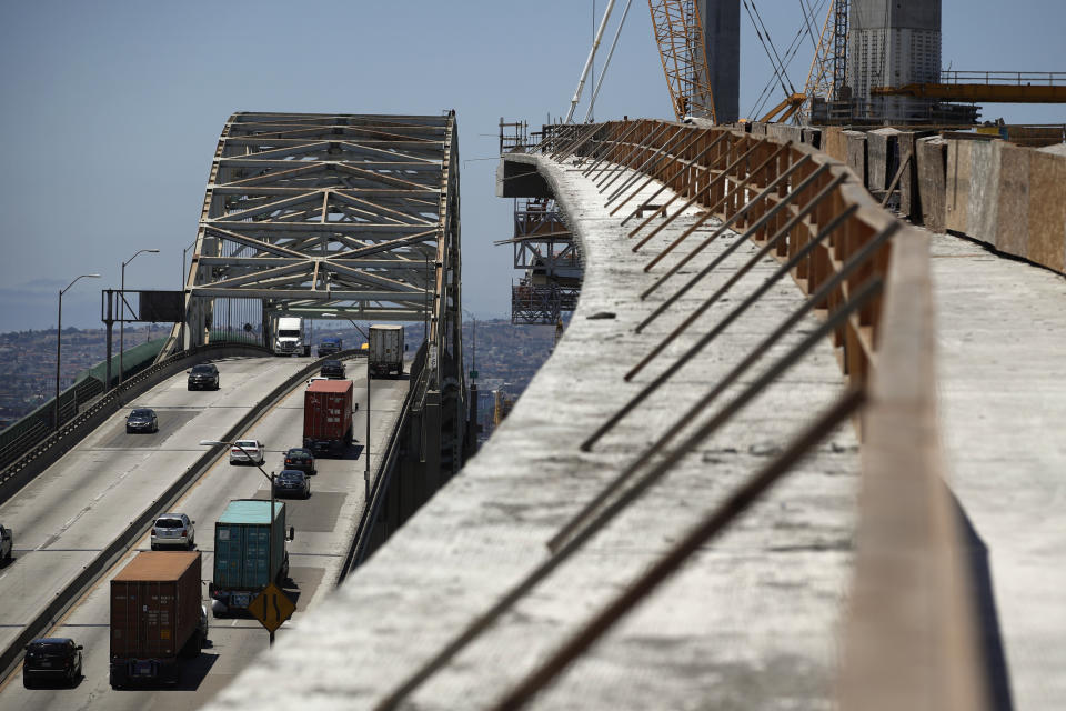 FILE - In this July 2, 2018, file photo, traffic moves on the old Gerald Desmond Bridge next to its replacement bridge under construction in Long Beach, Calif. President Donald Trump pronounced himself eager to work with Congress on a plan to rebuild America’s crumbling roads and bridges, but offered no specifics during his State of the Union speech on what kind of deal he would back. (AP Photo/Jae C. Hong, File)