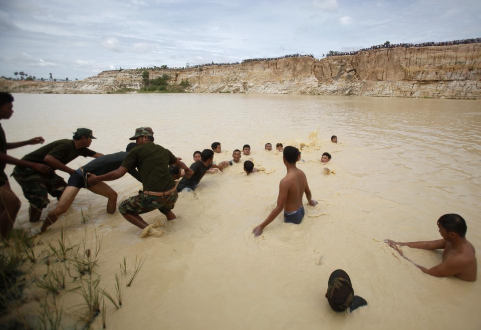 Rescue workers try to salvage parts of a Cambodian military helicopter which crashed on the outskirts of Phnom Penh July 14, 2014. The military helicopter crashed on Monday, killing five and injured one, police told Reuters. A Cambodian air force official said authorities are still investigating the cause of the crash. (REUTERS/Samrang Pring)