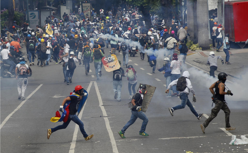 Manifestantes antigubernamentales se enfrentan con fuerzas de seguridad que les impiden el paso con gases lacrimógenos para que no lleguen al Consejo Nacional Electoral en Caracas, Venezuela, el miércoles 24 de mayo de 2017. (AP Foto/Ariana Cubillos)