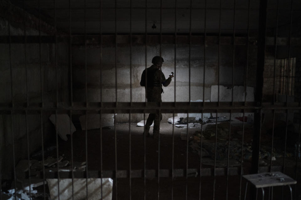 An Ukrainian serviceman stands in a basement which, according to Ukrainian authorities, was used as a torture cell during the Russian occupation, in the retaken village of Kozacha Lopan, Ukraine, Saturday, Sept. 17, 2022. (AP Photo/Leo Correa)