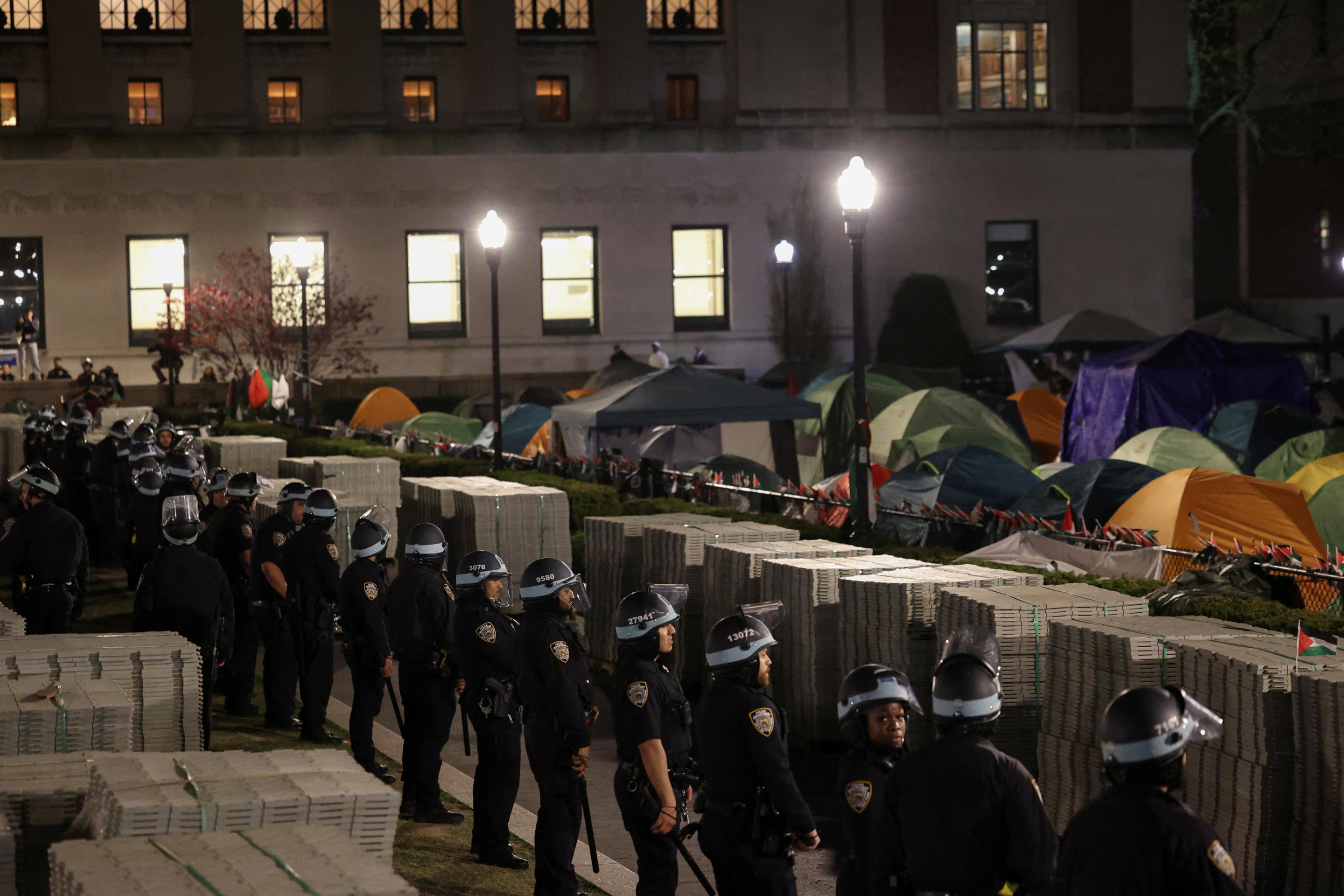 Police officers stand near an encampment of protesters.