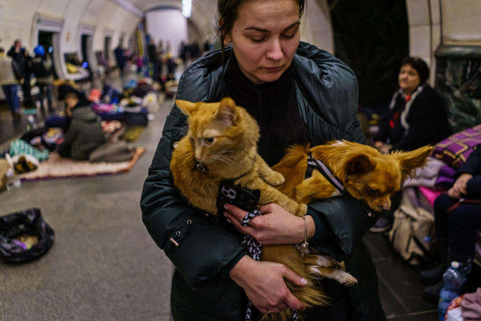 Julia Gereasumenko holds her cat and dog in her arms in a Kyiv subway station.