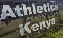 FILE - Junior athletes run past a sign for Athletics Kenya at the Discovery cross country races, an annual race held to identify up-and-coming new young talent, in Eldoret, Kenya on Jan. 31, 2016. World Athletics President Seb Coe said Wednesday, Nov. 30, 2022 that reports about a possible full-scale ban for Kenya due to a protracted doping crisis were misguided, and that increased funding and vigilance from the Kenyan government persuaded authorities to stop short of the most radical sanctions. (AP Photo/Ben Curtis, File)