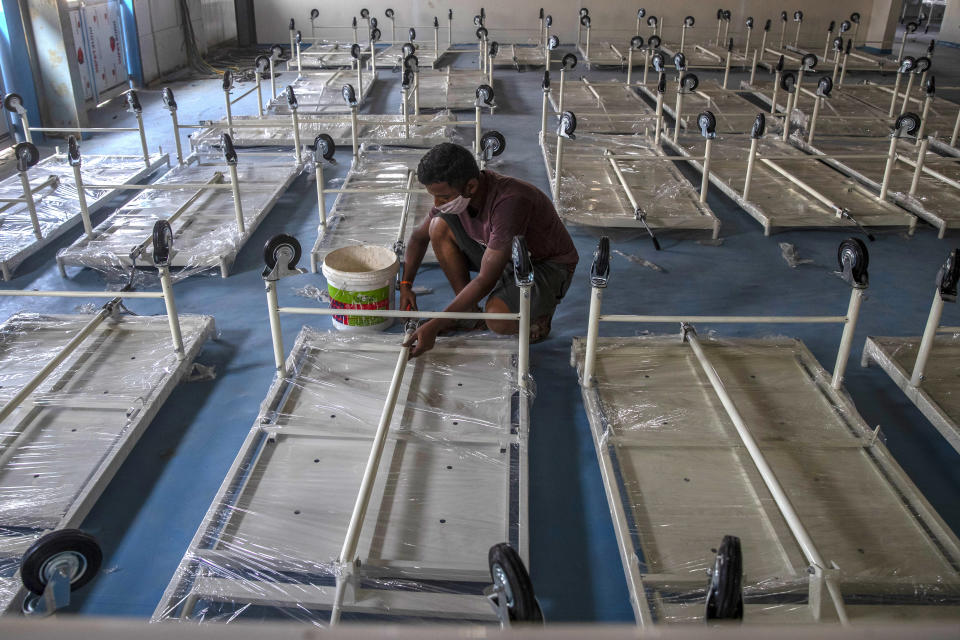 A workers installs a beds at a makeshift COVID-19 care center with 1200 beds in Mumbai, India, Friday, Dec. 31, 2021. In India, millions of people were planning to ring in the new year from their homes, with nighttime curfews and other restrictions taking the fizz out of celebrations in large cities including New Delhi and Mumbai due to a surge of coronavirus infections, many infected with contagious omicron variant. (AP Photo/Rafiq Maqbool)