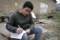 Mihaly Kovacs, a 12 year-old Hungarian boy, works on his homework outside his home in Bodvaszilas, Hungary, Monday, April 12,2021. Many students from Hungary's Roma minority do not have access to computers or the internet and are struggling to keep up with online education during the pandemic. Surveys show that less than half of Roma families in Hungary have cable and mobile internet and 13% have no internet at all. (AP Photo/Laszlo Balogh)