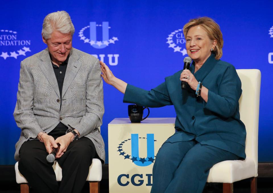 Former President Bill Clinton, left, listens as former Secretary of State Hillary Rodham Clinton speaks during a student conference for the Clinton Global Initiative University, Saturday, March 22, 2014, at Arizona State University in Tempe, Ariz. More than 1,000 college students are gathered at Arizona State University this weekend as part of the Clinton Global Initiative University's efforts to advance solutions to pressing world challenges. (AP Photo/Matt York)