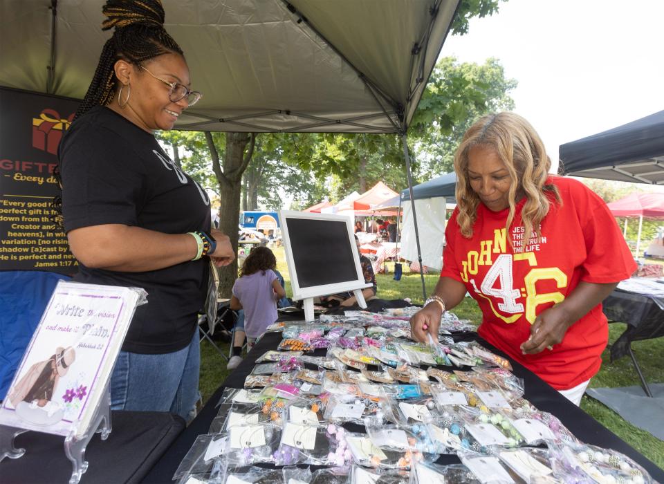 Stephanie Barrino, right, browses earrings at Quinnet White's Gifted 5QTS apparel stand Saturday at the Juneteenth Community Festival at Nimisila Park in Canton.