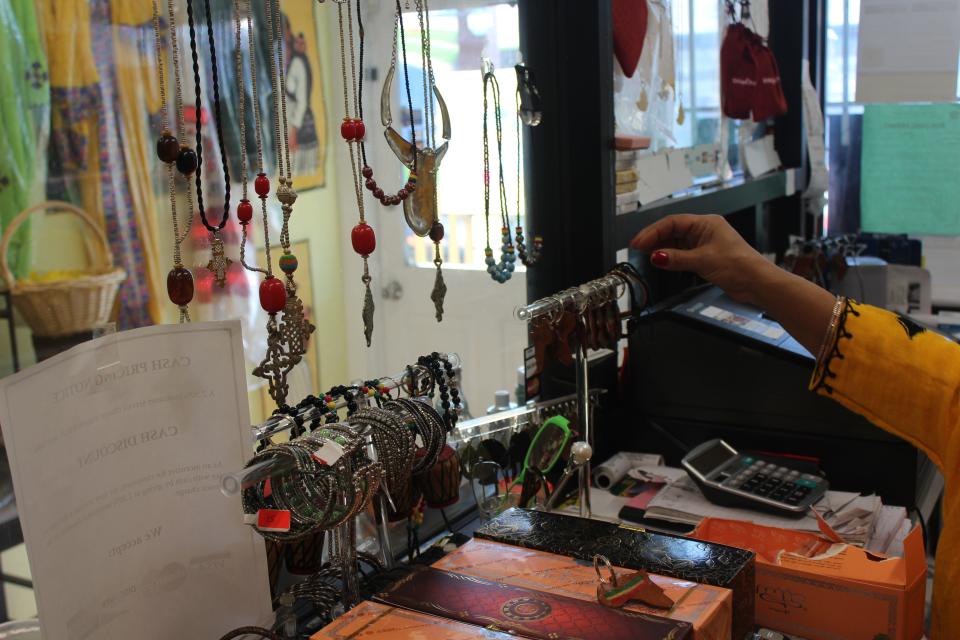 Frehiwot Mamo reaches for jewelry. Merkato Ethiopian Market & Grocery sells necklaces, bracelets and other items.