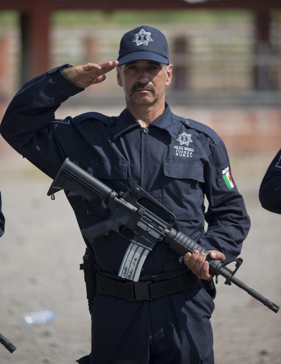 A member of a self-defense group salutes while standing in his newly-issued uniforms at a ceremony in Tepalcatepec, Mexico, Saturday, May 10, 2014. At the ceremony in the town where the vigilante movement began in February 2013, officials handed out new pistols, rifles and uniforms to 120 self-defense group members who were sworn into a new official rural police force. Mexico's government on Saturday began demobilizing the vigilante movement of assault-rifle-wielding ranchers and farmers that had succeeded in largely expelling the Knights Templar cartel from the western state of Michoacan when authorities couldn't. (AP Photo/Eduardo Verdugo)