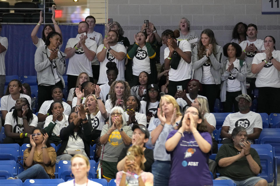 Baylor womens basketball players and staff, wearing white shirts with the letters "BG" on them, cheer as Phoenix Mercury center Brittney Griner was introduced for the Mercury's WNBA basketball game against the Dallas Wings, Wednesday, June 7, 2023, in Arlington, Texas. (AP Photo/Tony Gutierrez)