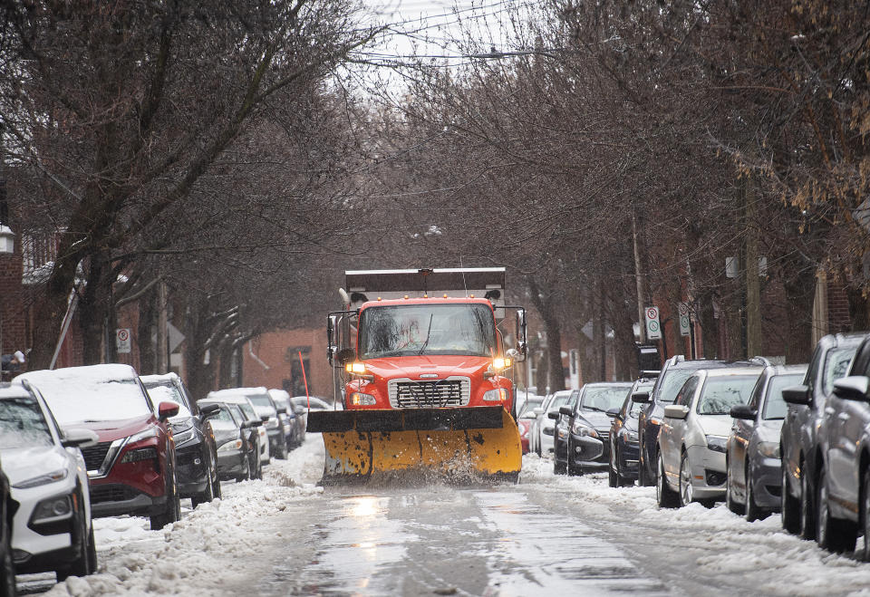 A plow clears water and slush from a street in Montreal, Friday, Dec. 23, 2022, as a storm system bears down on the region. (Graham Hughes /The Canadian Press via AP)