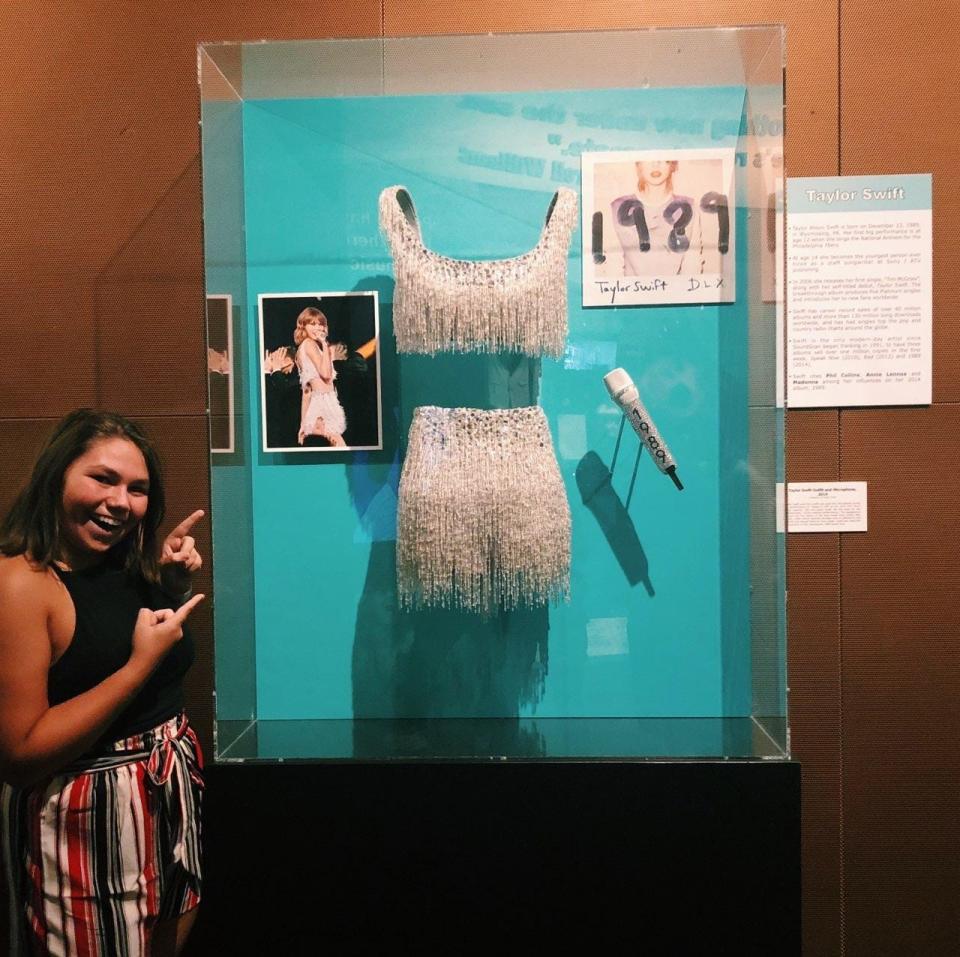 Swiftie Cassidy Werkheiser stands with the Taylor Swift display at the Rock and Roll Hall of Fame.