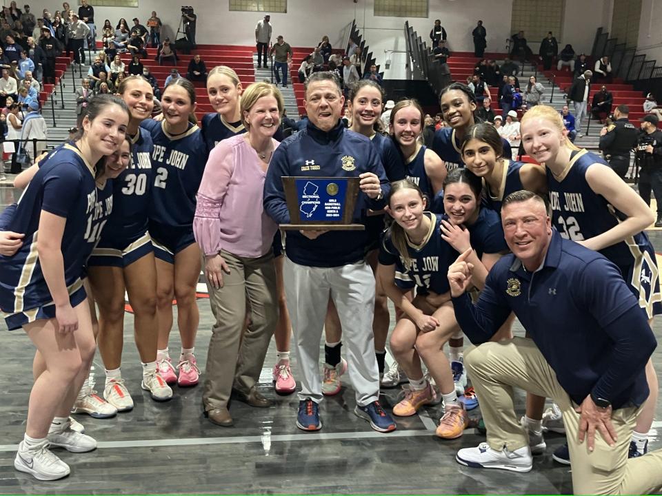 NJSIAA North Non-Public A girls basketball final at Kennedy High School (Paterson) on Monday, March 4, 2024. First-year coach Peter Torres (with trophy) and Pope John XXIII celebrate defeating Immaculate Heart for the program's first sectional title since 1998.