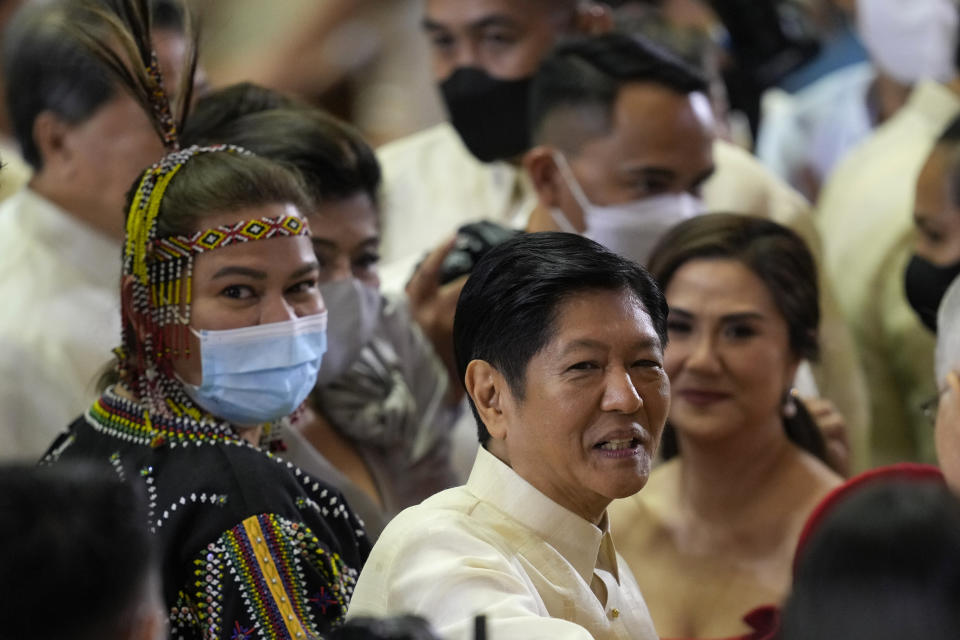 New Philippine President Ferdinand Marcos Jr., center, stands beside Vice President Sara Duterte, left, in a traditional tribal dress after his first state of the nation address in Quezon city, Philippines, Monday, July 25, 2022. Marcos Jr. delivered his first State of the Nation address Monday with momentum from his landslide election victory, but he's hamstrung by history as an ousted dictator’s son and daunting economic headwinds. (AP Photo/Aaron Favila, Pool)