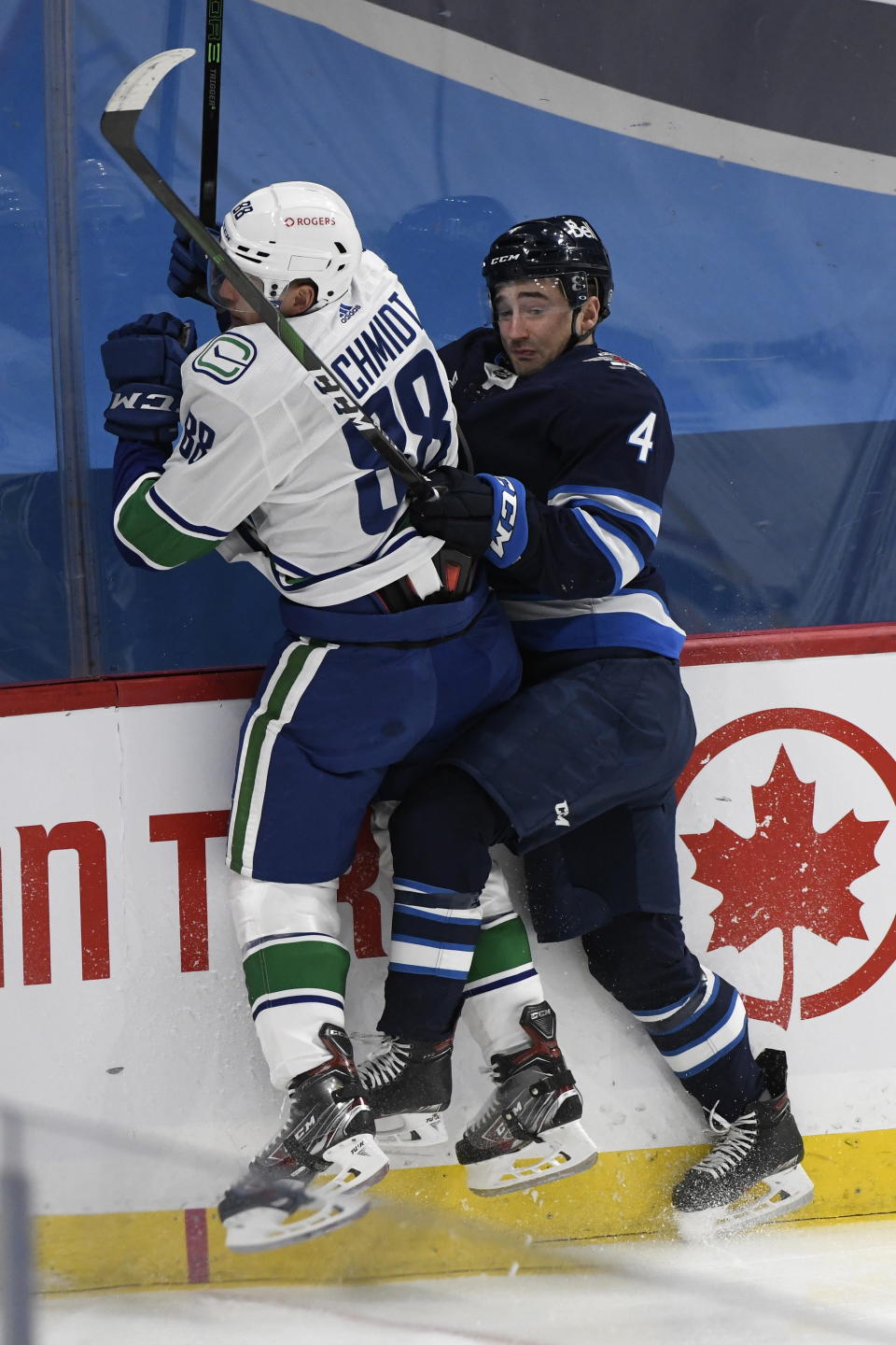 Winnipeg Jets' Neal Pionk (4) checks Vancouver Canucks' Nate Schmindt (88) during first period NHL hockey action in Winnipeg, Manitoba on Tuesday March 1, 2021. (Fred Greenslade/The Canadian Press via AP)