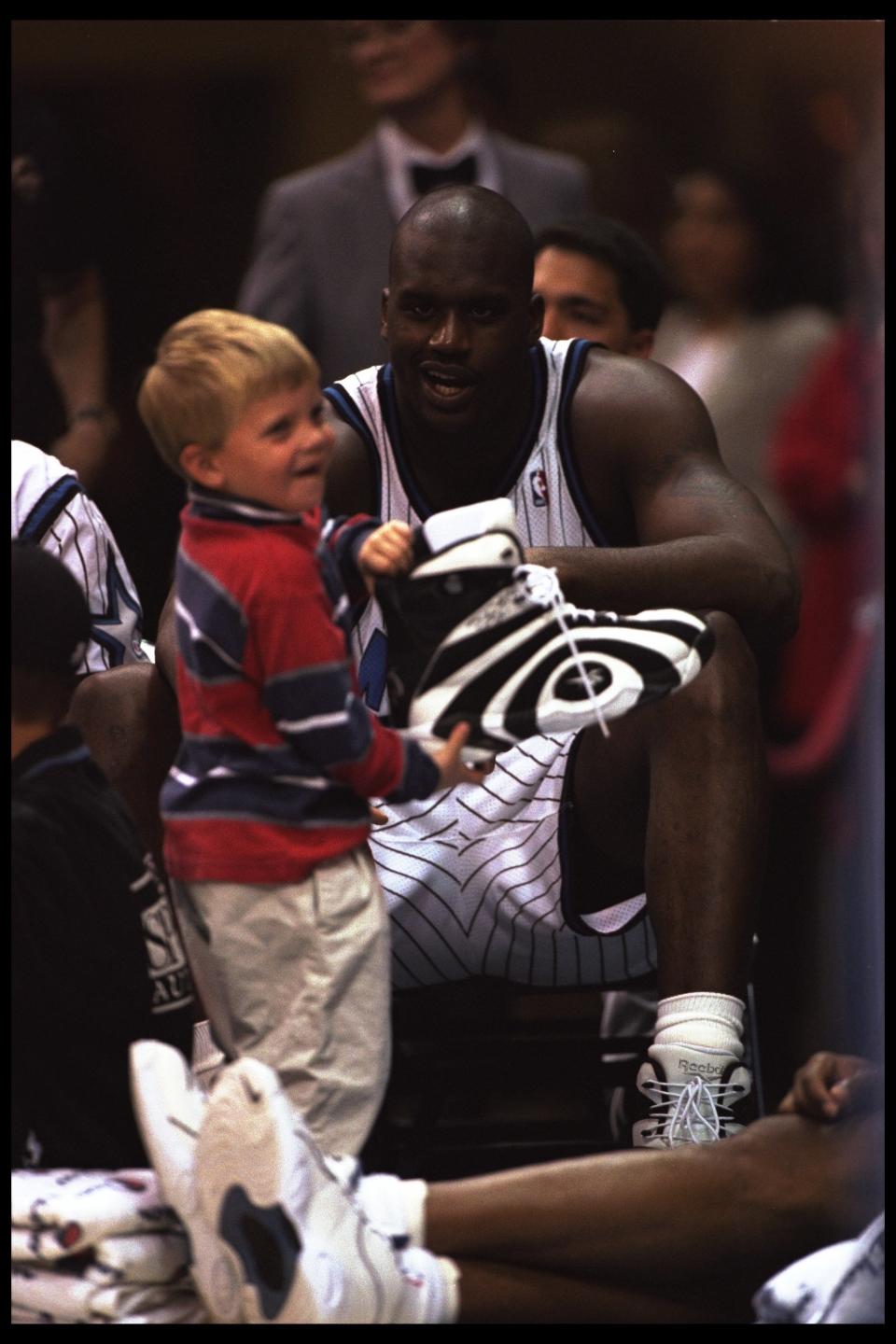 Shaquille O'Neal talks with a young fan during a game against the Milwaukee Bucks played at the Orlando Arena in Orlando, Florida on February 16, 1996. The Magic won the game, 121-91.