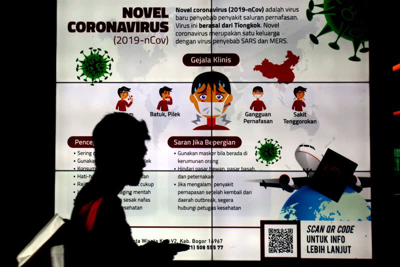A man passes by an informational signage about the coronavirus, at a hospital in Bogor, near Jakarta, Indonesia