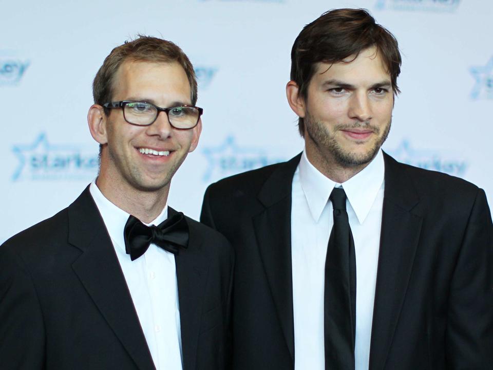 <p>Adam Bettcher/Getty</p> Twin brothers Michael Kutcher and Ashton Kutcher walk the red carpet in July 2013.