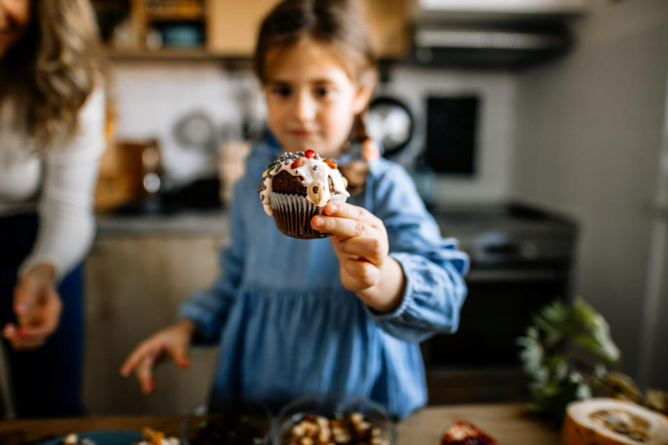 A little girl holds up a cupcake