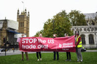 Demonstrators wearing pig masks hold a banner against the tread deal between the UK and the US, in Parliament Square, as part of a day of action against the US trade deal, ten days before the US Presidential election, in London, Saturday, Oct. 24, 2020. There will will be protests held nationwide against a proposed US trade deal, opposed by a number of organisations including Global Justice Now and Stop Trump Coalition. (AP Photo/Alberto Pezzali)