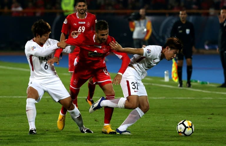 Kashima Antlers defender Jung Seunghyun (R) fights for the ball with Persepolis' midfielder Ahmad Nourollahi (C) during the second leg of the AFC Champions League final football match on November 10, 2018 at the Azadi Stadium in Tehran