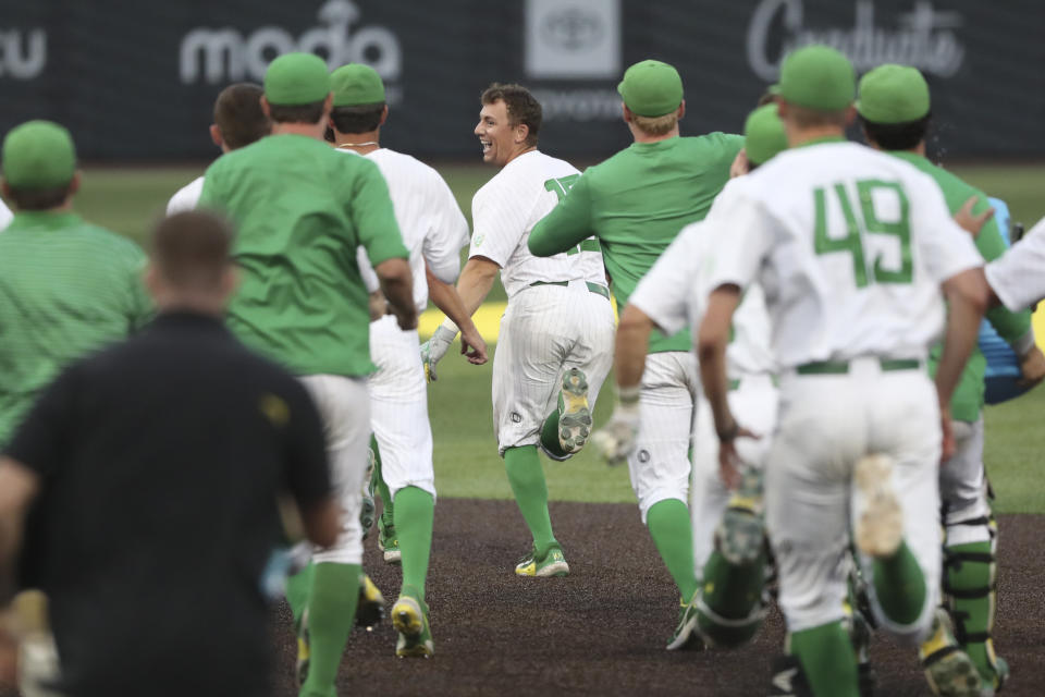 Oregon's Drew Cowley, center, is chased by teammates after he drove in the winning run against Oral Roberts during an NCAA college baseball tournament super regional game Friday, June 9, 2023, in Eugene, Ore. (AP Photo/Amanda Loman)