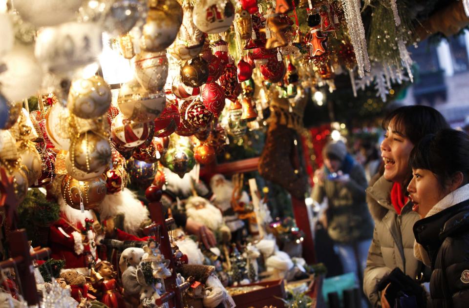 Tourists from Japan look at Christmas decorations on a stall at the opening day of Germany's oldest Christkindlesmarkt (Christ Child Market) in Nuremberg November 29, 2013. The first official record of this pre-Christmas market dates back to 1628. A list of notices for stall holders from 1737 shows that almost all of Nuremberg's craftsmen were represented. Every year, Germany's traditional markets, such as the centuries-old Christkindlesmarkt in medieval Nuremberg, draw millions of visitors, both local and foreign. They open before the first Sunday of Advent and usually continue until December 24 at noon. REUTERS/Michaela Rehle (GERMANY - Tags: SOCIETY ENTERTAINMENT)