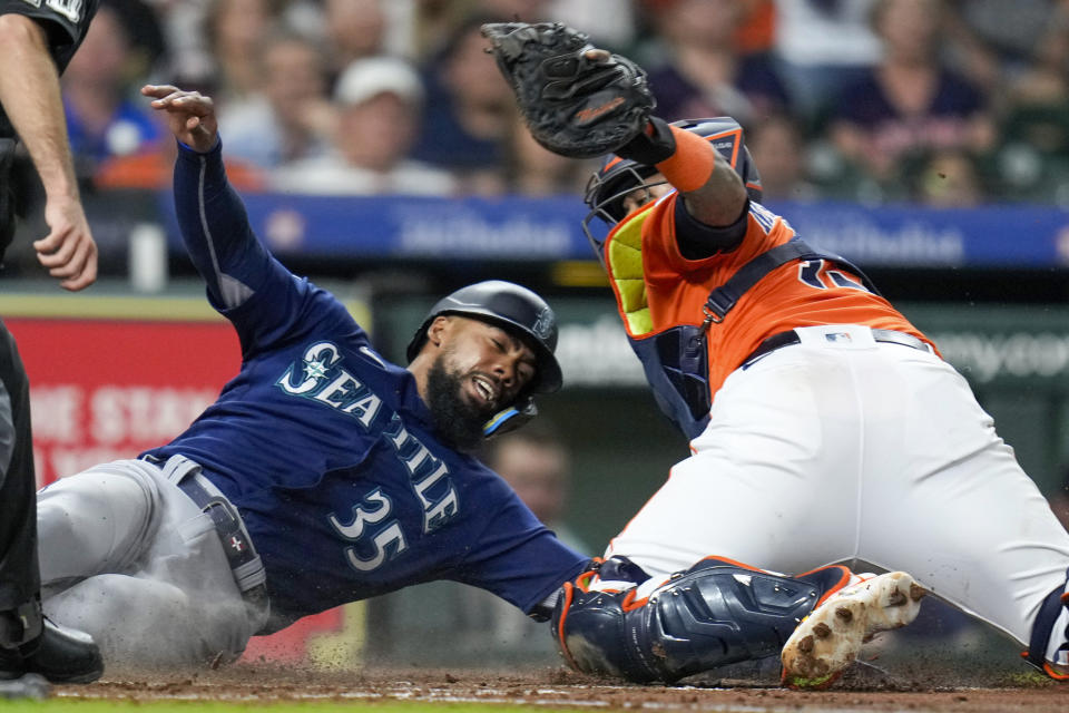 Seattle Mariners' Teoscar Hernandez (35) is tagged out at home by Houston Astros catcher Martin Maldonado, right, during the fourth inning of a baseball game, Friday, Aug. 18, 2023, in Houston. (AP Photo/Eric Christian Smith)