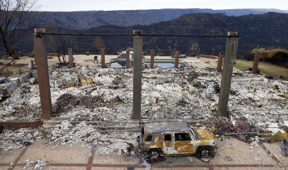 FILE - In this Dec. 3, 2018, file photo, a vehicle rests in front of a home leveled by the Camp Fire in Paradise, Calif. An effort to block Pacific Gas and Electric's path out of bankruptcy kicked off the trial Wednesday, May 27, 2020, on the plan in bankruptcy court as critics of the utility questioned whether the overwhelming vote in favor of the plan by wildfire victims was tainted by conflicts of interest and shoddy counting. PG&E's plan won support last week in a landslide, with victims overwhelmingly backing PG&E's $58 billion proposal to emerge from bankruptcy after 18 months. (AP Photo/Noah Berger, File)