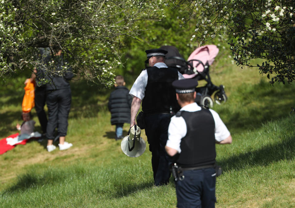 A police officer with a megaphone instructs people to keep moving in Greenwich Park, London, as the UK continues in lockdown to help curb the spread of the coronavirus.