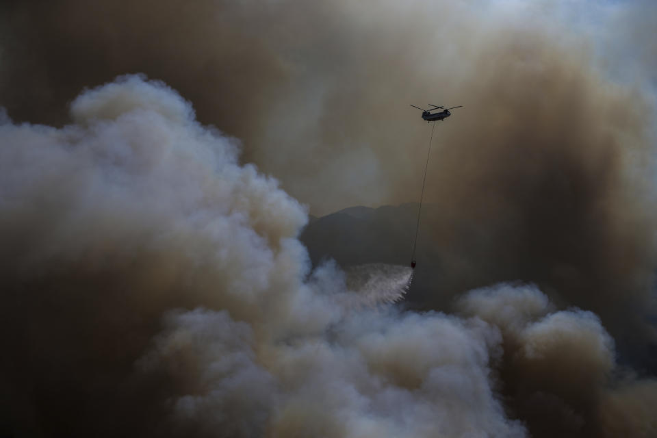 A helicopter drops water over a wildfire in Koycegiz, Mugla, Turkey, Monday, Aug. 9, 2021. (AP Photo/Emre Tazegul)