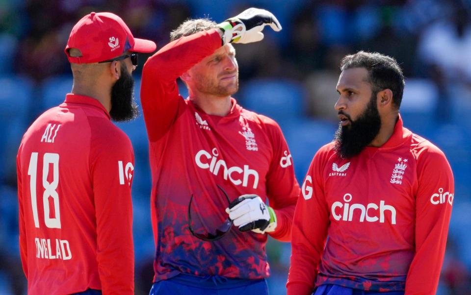 England's bowler Adil Rashid, right, celebrates with Moeen Ali and captain Jos Buttler the dismissal of West Indies' Shai Hope during the third T20 cricket match at National Cricket Stadium in Saint George's, Grenada, Saturday