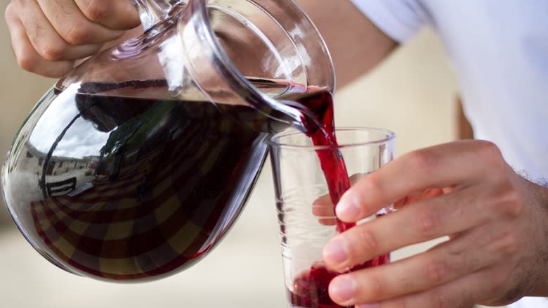 Man pouring red wine into a tumbler